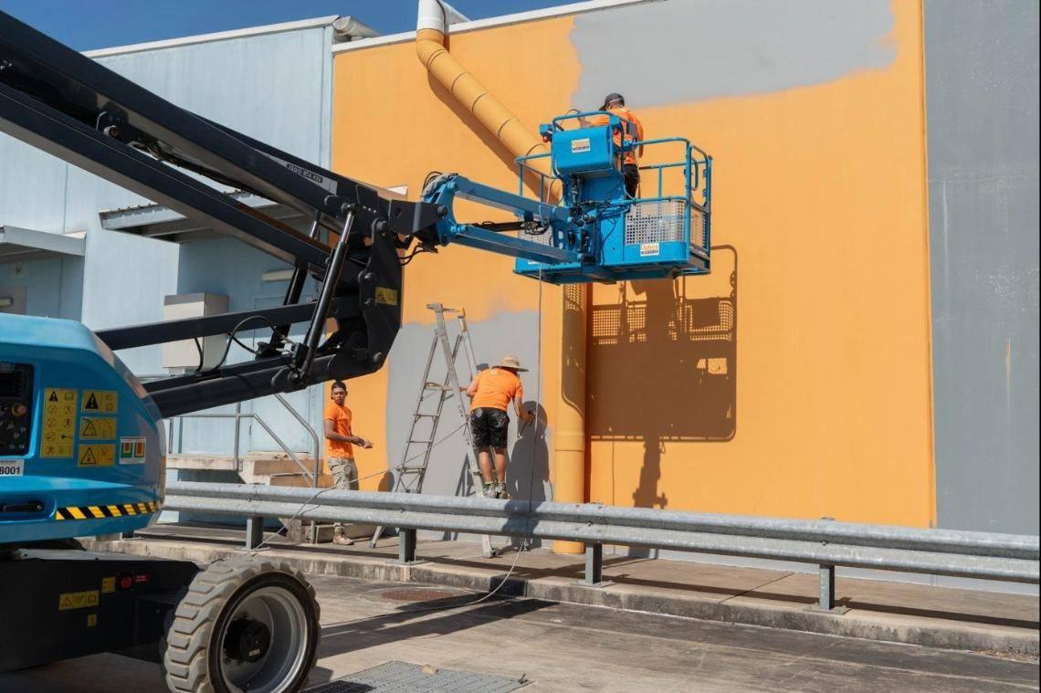 Painters on a boom lift repainting a supermarket facade